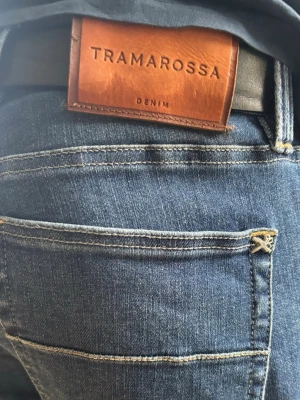 Blå jeans från Tramarossa -  Tramarossa, “Michelangelo Zip SS”-modellen. Perfekt tvätt och komfort med lyxiga detaljer. 🧵 Märke & Modell: Tramarossa – Michelangelo Zip SS 📏 Storlek & Passform: 33, slim-straight. 🧩 Material: Premium denim, 91% bomull / 5% polyester / 4% elastan 📐 Mått: Midja 45 cm, innerben 84 cm, ytterben 112 cm ✅ Skick: 7/10, fint skick, patchen har färgat av sig lite på insidan vid tvätt men inget som syns vid användning, denimet vid grenen är oxå lite tunnare  💰 Nypris ca 4000 kr ‼️Skickas inom 24h‼️
