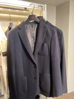 Marinblå kavaj - Stilren mörkblå kavaj med två knappar framtill och tre utanpåliggande fickor. Perfekt nu till våren som kavaj men fungerar också som overshirt☀️Tidlös siluett som man lätt kan klä upp och klä ner. Modellen är 184cm, hör av er vid frågor!