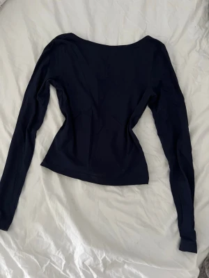 Mörkblå långärmad topp - En enkel och stilren mörkblå långärmad topp med enkel öppen rygg. Toppen har en figurnära passform och är tillverkad i ett mjukt, stretchigt material som känns bekvämt mot huden. Man kan även vända på den så man får det öppna framåt😊