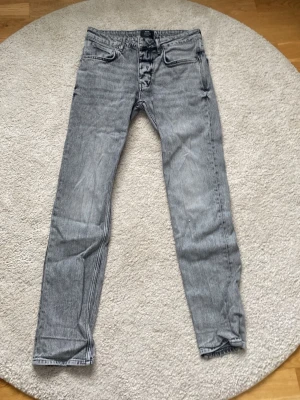 Grå slim fit jeans från Neuw - Säljer ett par grå slim fit jeans från Neuw med klassisk femficksmodell och snygg tvättad look. Jeansen har normal midja, dragkedjegylf och silverfärgade detaljer. Perfekta för en avslappnad men ändå stilren outfit. Med längden 32