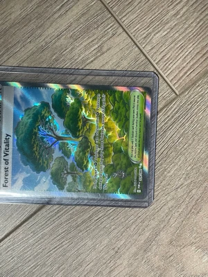 Forest of Vitality holografiskt kort - Säljer ett holografiskt samlarkort 'Forest of Vitality' från MetaZoo. Kortet har färgstarka illustrationer av träd och natur med glittrande effekt. Perfekt för dig som gillar samlarkortspel och vill ha något unikt i din samling.