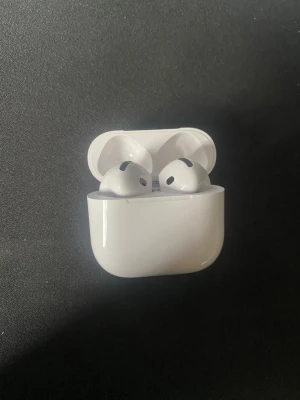Airpods 4 ANC - Säljer ett par vita Apple AirPods 4 med aktiv brusreducering (ANC). De är trådlösa in-ear hörlurar med laddningsetui i blank plast. Snygg och stilren design som passar perfekt till mobilen eller datorn. Laddningsetui med LED-indikator.