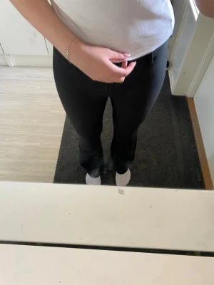 Svarta kostymbyxor med raka ben - Snygga svarta kostymbyxor med raka ben och klassiska bälteshällor. Byxorna har en stilren look och är perfekta till en dressad outfit. Materialet ser ut att vara en mjuk och lite stretchig bomullsblandning. Passar dig som gillar enkel och tidlös stil.