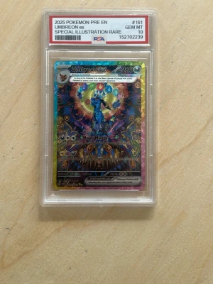 Umbreon ex Pokémonkort PSA 10 - Säljer ett Umbreon ex special illustration rare Pokémonkort från 2025, graderat PSA 10 GEM MT. Kortet har färgstark design med holografiska detaljer och är inneslutet i ett skyddande plastfodral. Perfekt för samlare eller Pokémonfans.