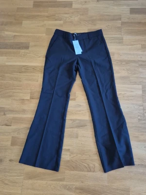 Svarta bootcut kostymbyxor Gina Tricot - Snygga svarta kostymbyxor från Gina Tricot i bootcut-modell. Byxorna har låg/medelhög midja, pressveck och vida ben. Säljer pga fel storlek.