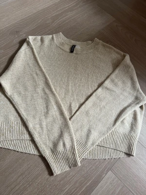 Beige stickad tröja från H&M - Säljer en stilren beige stickad tröja från H&M med rund halsringning och långa ärmar. Tröjan har ribbade muddar vid ärmslut och nederkant, perfekt för lager-på-lager och en avslappnad look.