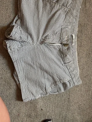 Randiga shorts från Gap - Snygga randiga shorts från Gap i vitt och blått. Klassisk passform med dragkedja och knapp framtill. Perfekta för varma dagar och har en fräsch, somrig look. Tillverkade i mjuk bomull för extra komfort.