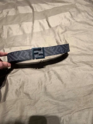 Fendi bälte - Snyggt svart bälte från Fendi med klassiskt FF-mönster och ett stort metallspänne med Fendi-logga. Bältet är gjort i skinn och har en stilren design som passar till många outfits. Hör av er vid frågor och funderingar. Bältet är i bra skick men har slitits lite vid 2 hål kan skicka bild på det i chatten