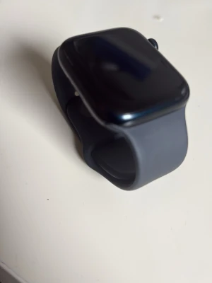 Apple Watch med svart silikonarmband - Snygg Apple Watch med svart fyrkantig urtavla och matchande svart silikonarmband. Model: Apple Watch Series 7