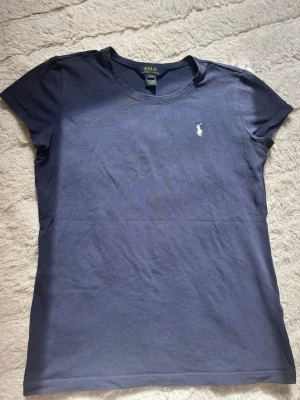 Marinblå t-shirt från Polo Ralph Lauren - Snygg marinblå t-shirt från Polo Ralph Lauren🩵🩵superfin att matcha med en kjol nu till våren/sommaren!! Passar som en xs/s