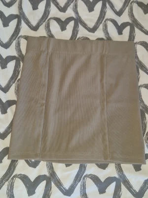Kjol kort modell - Snygg beige kortkjol i lite ribbad material med diskreta vertikala sömmar framtill. Kjolen har en enkel och stilren design som passar perfekt till många olika outfits. Materialet är mjukt och ger en trendig vintagekänsla. Enbart testad