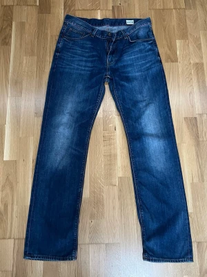 Mörkblå jeans från Tommy Hilfiger W35 L34 - Snygga mörkblå jeans från Tommy Hilfiger med klassisk femficksmodell och raka ben. Jeansen har diskreta slitningar framtill och kontrastsömmar. Tillverkade i slitstarkt denim med en cool tvättad look. Perfekta för en avslappnad och trendig stil. Pris kan snackas vid snabbt köp! :)