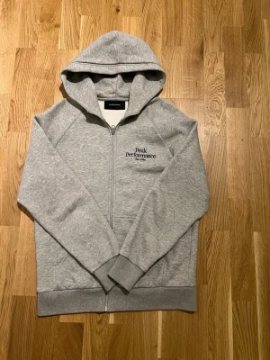 Peak Performance Hoodie - Stilfull Hoodie från Peak Performance för män. Koftan är i nyskick inga skador/slitage eller några defekter, Storlek M. Väldigt bekväm och skön hoodie som passar till alla tillfällen, en ny i butik kostar 1299 kronor. Hör av er vid intresse/funderingar. PRIS KAN DISKUTERAS!