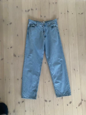 Ljusblåa raka jeans - Säljer ett par ljusblå jeans med rak passform och klassisk femficksdesign. Jeansen har hög midja och är tillverkade i ett robust denimtyg. Perfekta för en avslappnad och trendig look.   Använda få väldtigt få gånger 
