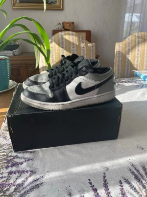 Nike Air Jordan 1 Low svart/grå - Snygga Air Jordan 1 Low sneakers i svart och grått läder med klassisk Nike Swoosh på sidan och Air Jordan-logga på hälen. Lågt skaft och svarta skosnören. Perfekta för dig som gillar streetwear och ikoniska sneakers.Dem är använda men fortfarande i bra skick.Orginal boxen hänger med. Storlek 42,4
