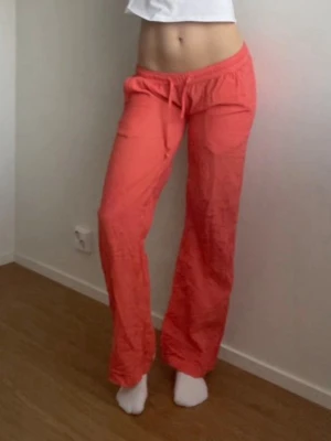 Koralrosa mjukisbyxor med dragsko - Säljer ett par korallrosa linnebyxor med raka ben och dragsko i midjan. Byxorna har resår i midjan och en bakficka. 