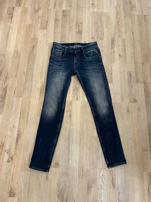 Mörkblå Replay jeans - Säljer ett par mörkblå slim fit Replay jeans i modellen anbass  med snygga slitningar och klassisk femficksdesign. Jeansen har en något tvättad look och raka ben. Perfekta för dig som gillar en stilren och modern look. Pris ej hugget i sten och hör av dig vid frågor