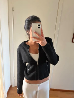 Svart zip-kofta från  - Säljer en svart kofta med dragkedja framtill och två dragkedjeförsedda fickor. Koftan har ribbade muddar. I strl M men passar mig som använder S/XS