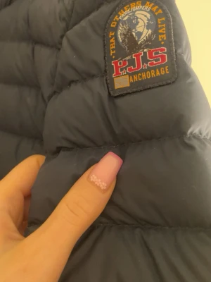 Mörkblå dunjacka från Parajumpers - Snygg mörkblå dunjacka från parajumper. Perfekt för kalla vinterdagar och har en stilren, rak passform. 2 st inne fickor och även två gömda fickor under armarna utepå jackan , storlek S passar även XS säljer för jag köpt en likadan i annan färg inte sönder nånstans ser ut som ny , köpare står för frakt och pris kan sänkas vid snabb affär 