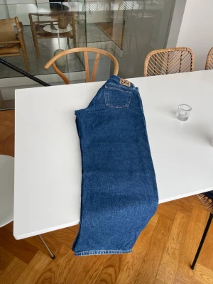 Blåa raka jeans från Crocker - Säljer ett par klassiska blåa jeans  med rak passform och hög midja. Jeansen har fem fickor, bälteshällor och snygga kontrastsömmar. Materialet är kraftig denim i 100% bomull. Perfekta för en avslappnad och trendig look.