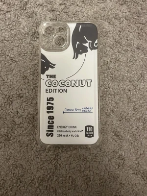 Coconut Edition mobilskal transparent - Snyggt mobilskal med tryck 'The Coconut Edition' och cool design inspirerad av energidryck. Skalet är transparent med svart och vit text och grafik, har förstärkta hörn och passar en mobil med trippelkamera. Perfekt för dig som vill sticka ut med ett unikt skal.