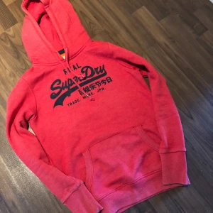 Röd ovanlig superdry hoodie - Tja! Säljer en riktigt fet röd hoodie från superdry. Storlek S på taggen men passar och sitter som en XS. Slim passform. Hör av dig vid minsta fundering!