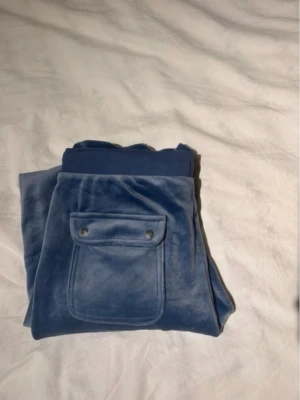 Blå velourbyxor från Juicy Couture - Mysiga blå Juicy Couture byxor som säljs pga av att dem ej används och är för stora. Dem är använda ungefär 2 gånger.