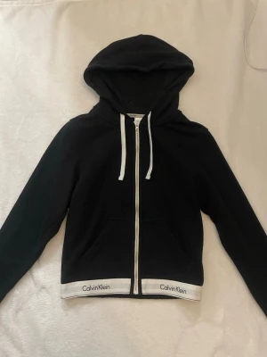 Svart hoodie från Calvin Klein - Svart zip hoodie från Calvin Klein. Storlek xs. Använd en gång men ser helt ny ut! Pris går att diskuteras!