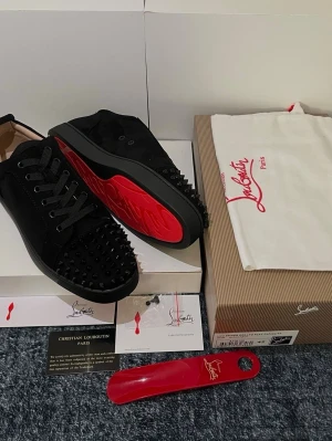 Christian Louboutin  - Säljer ett par svarta sneakers från Christian Louboutin med svarta nitar över tån och sidorna. Skorna har fettttta blodiga sulor🩸🤙, Perfekta för sommar ☀️ Pris kan diskuteras🙌