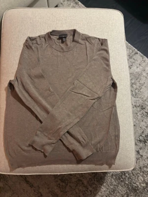 Brun tunn tröja från H&M - Säljer en enkel och stilren brun tröja från H&M. Tröjan har rund halsringning, långa ärmar och är tillverkad i ett tunt, mjukt material som passar perfekt för lager på lager. Klassisk passform och ribbade muddar vid ärmslut och nederkant. Storlek M.
