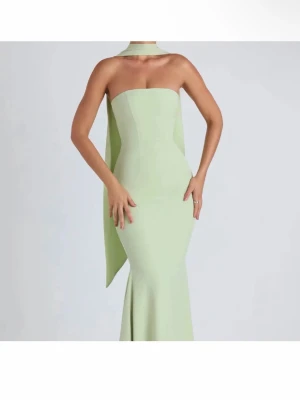 Ljusgrön axelbandslös maxiklänning - Ljusgrön maxiklänning med axelbandslös design och figurnära passform. Klänningen har en lång, elegant scarfdetalj som hänger från halsen ner längs ryggen. Endast använd vid 1 tillfälle🤍