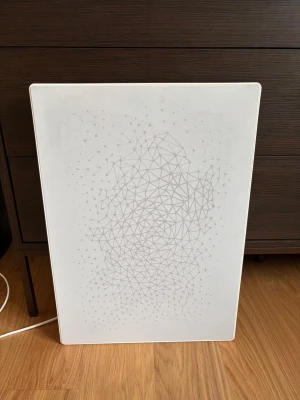 IKEA symfonisk tavelhögatalare SONOS - Säljer en vit SONOS IKEA SYMFONISK WiFi-högtalare med meshfront och geometriskt mönster. Högtalaren har en rektangulär form och kan placeras både stående och liggande. Perfekt för att streama musik trådlöst och smälter in som en tavla i rummet.  
