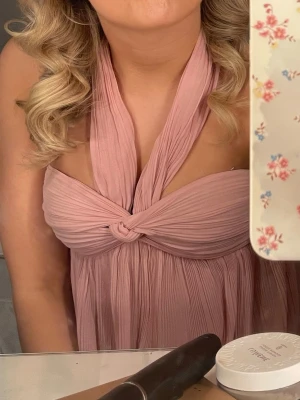 Ljusrosa halterneckklänning - Supersöt ljusrosa klänning med halterneck och twistad detalj framtill. Klänningen har ett luftigt, plisserat tyg som ger en romantisk känsla och faller snyggt. Perfekt för sommarens alla tillfällen! Säljs ej längre.