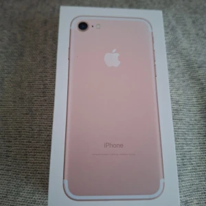 iPhone 7 i roséguld med box - Säljer en snygg iPhone 7 i roséguld. Telefonen har en stilren design med rundade kanter, metallbaksida och vit framsida. Kommer i originalförpackning. Perfekt för dig som vill ha en smidig och klassisk iPhone.