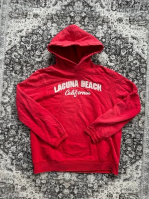 Levi’s hoodie Laguna Beach California🌴🏄‍♂️ - Snygg röd hoodie från Levi’s texten 'Laguna Beach California' broderat i vitt och vitt/skrivstil framtill. Den är i bra skick! Storlek M. För mer info är de bara att skriva!