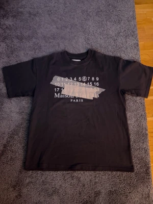 Maison margiela T-shirt  - Säljer en sjukt fet T-shirt från maison margiela. Den är knappt använd och är i nyskick. Frågor? Kontakta mig, allt gott, mvh Noah154. PS, KÖP INTE MED INSTABOX OM NI VILL HA VARAN SNABBT‼️