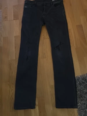 Disel jeans straigh fit.  - Säljer ett par svarta jeans med raka ben och slitningar på båda benen. Jeansen har klassisk femficksdesign och knappgylf. Materialet är denim med en något stretchig känsla. Perfekta för en avslappnad och trendig look. Köpt för 1700