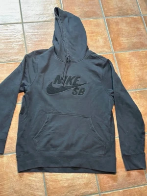 Nike SB Hoodie - Nike SB skate hoodie i svart. Använd en del men i bra skick. Mjukt och skönt material. Har en ficka anpassad för mobil (syns på bilder). Storlek L  Nike SB skate hoodie in black. Used a bit but in good condition. Very nice and comfortable material. Has a phone pocket (shown in pictures). Size L