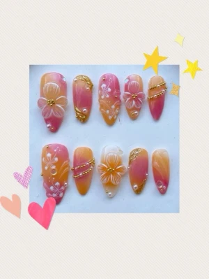 Press-on naglar med blommor och pärlor - Gör på beställning! Snygga press-on naglar i mandelform med rosa och orange ombre, dekorerade med vita handmålade blommor, små pärlor och guldfärgade detaljer. Perfekt för dig som vill ha en unik och kreativ nagelstil.