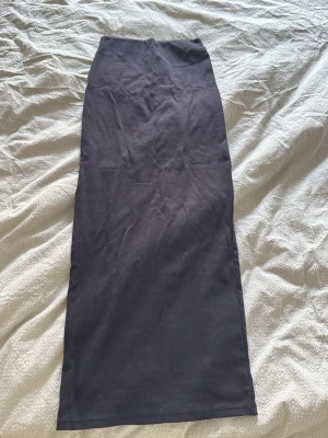 Svart långkjol från Gina Tricot - Rak svart långkjol från Gina Tricot i mjuk bomull. Kjolen har en enkel och stilren design utan mönster eller detaljer, perfekt för en clean och avslappnad look.