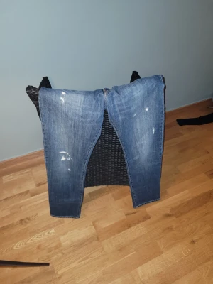 J.lindberg - Säljer ett par blå jeans med raka ben och slitna detaljer framtill. Jeansen har klassisk femficksdesign och är tillverkade i denim. Perfekta för en avslappnad och trendig look.Aldrig använda!