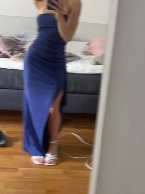 Marinblå balklänning med slits 💙 - Säljer min jättefina balklänning💙 Klänningen har en jättefin marinblå färg med axelbandslös design och hög slits på sidan. Figurnära i passformen med stretchigt, luftigt material som lägger sig följsamts och formar sig fint mot kroppen 🥰 Klänningen har insytt resor runt bysten så den håller sig på plats utan axelband. Jag är 158cm lång och den går precis ner till marken för mig, perfekt med klackar 😍 Storlek XS men skulle passa allt från XXS-S pga det följsamma, stretchiga materialet.