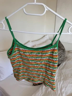Färgglad virkad topp - Säljer en handvirkad linnetopp med smala axelband i grönt. Materialet känns som bomull och toppen är croppad i modellen. Köpt i London i en vintagebutik för ca 900kr