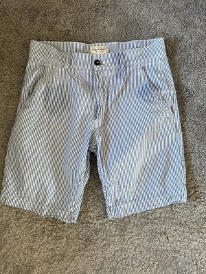 Randiga shorts från Bruun & Stengade - Snygga blå- och vitrandiga shorts från Bruun & Stengade. Klassisk passform med fickor på sidorna och knappgylf. Perfekta för sommaren och tillverkade i ett lätt bomullstyg som känns fräscht och luftigt.
