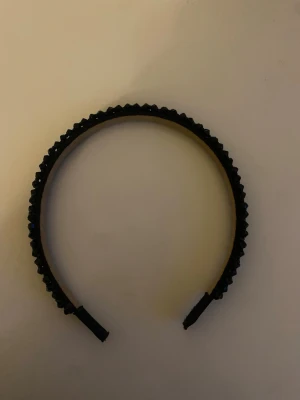 Svart diadem med glittrande pärlor - Snyggt svart diadem dekorerat med små glittrande pärlor som ger en lyxig känsla. Diademet har en klassisk form och är täckt med svarta pärlor i plast som reflekterar ljuset. Perfekt accessoar för att lyfta din look. Använd 3 gånger. 