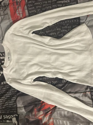 Vit ribbad långärmad tröja  - Säljer en enkel och stilren vit långärmad tröja från. Tröjan är ribbad och har en rund halsringning. Perfekt basplagg att matcha med olika outfits och funkar året runt.