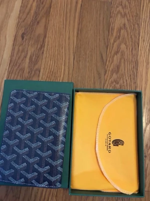 Mörkblå plånbok i läder - Snygg mörkblå plånbok  med det klassiska vita och gråa mönstret. Plånboken är tillverkad i läder och har flera kortfack på insidan. Kommer i original grön box och gul dustbag 