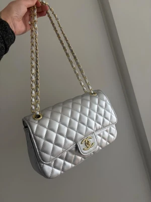 Silvrig väska  - Super fin stilren väska, man kan ha banden som på bilden eller längre. Den är aldrig använd. 