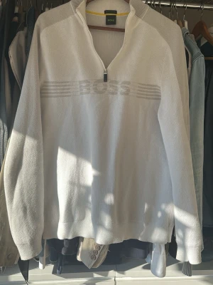 Vit halvzip tröja från BOSS - Vit långärmad tröja från BOSS med halvzip och ribbad krage. Tröjan har diskret BOSS-logga och ränder över bröstet. Tillverkad i mjukt material som känns skönt mot huden. Perfekt för en clean och stilren look. Köptes från U&M på väla för 2000kr. Säljer nu för 1000kr och går inte lägre då det är en väldigt exklusiv Boss tröja som man inte hittar längre. Storlek M-S, den ser kanske lite skrynklig ut men det är för den bara har legat i min garderob utan att användas. Jag löser dedär innan leverans.