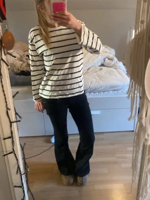 Randig långärmad t-shirt - Vit långärmad t-shirt med svarta horisontella ränder. Klassisk och enkel design med avslappnad passform. Perfekt till jeans eller kjol för en chill look. Använd en gång. Storlek 146/152 men passar mig som är ca 160 och bär XS